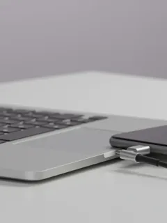 USB-C cables connecting laptop and smartphone on modern desk